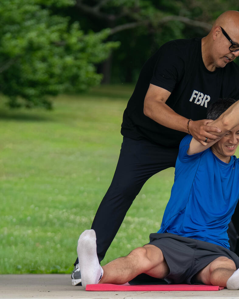 Assisted Stretching Rafael Jimenez assisting participant with an overhead side stretches using Pilates rings.