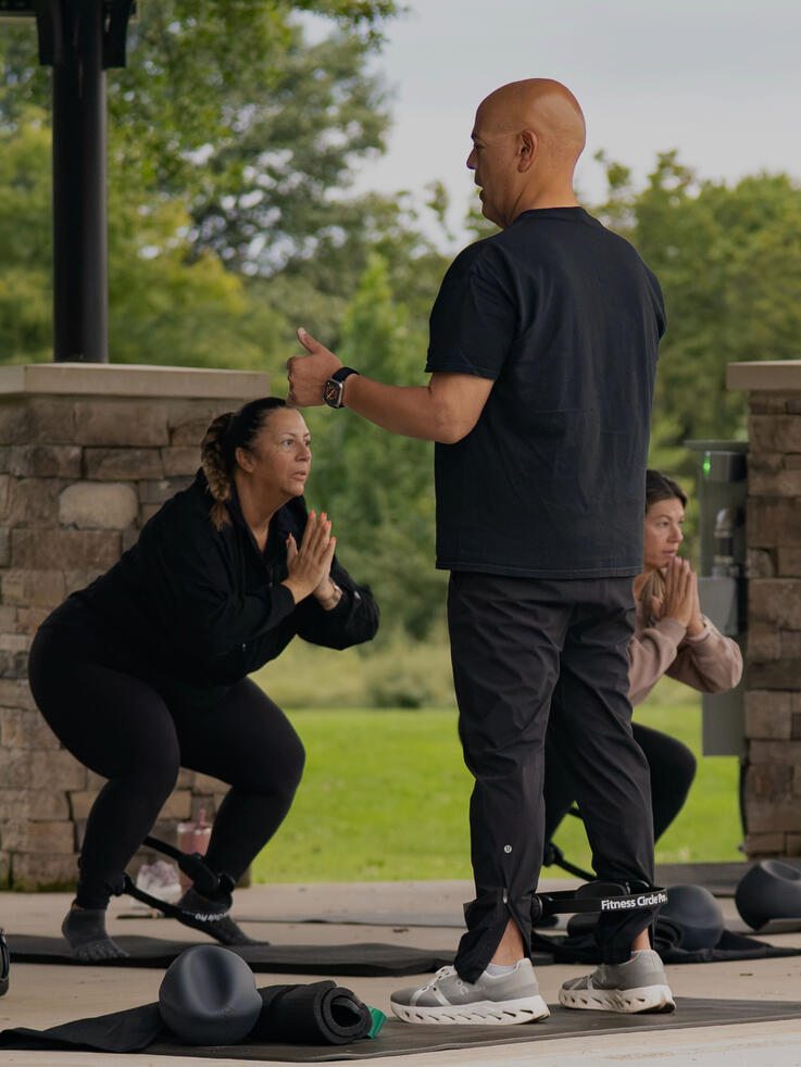 Instructor Rafael Jimenez Guiding Class Participants doing lower body work with the ring.